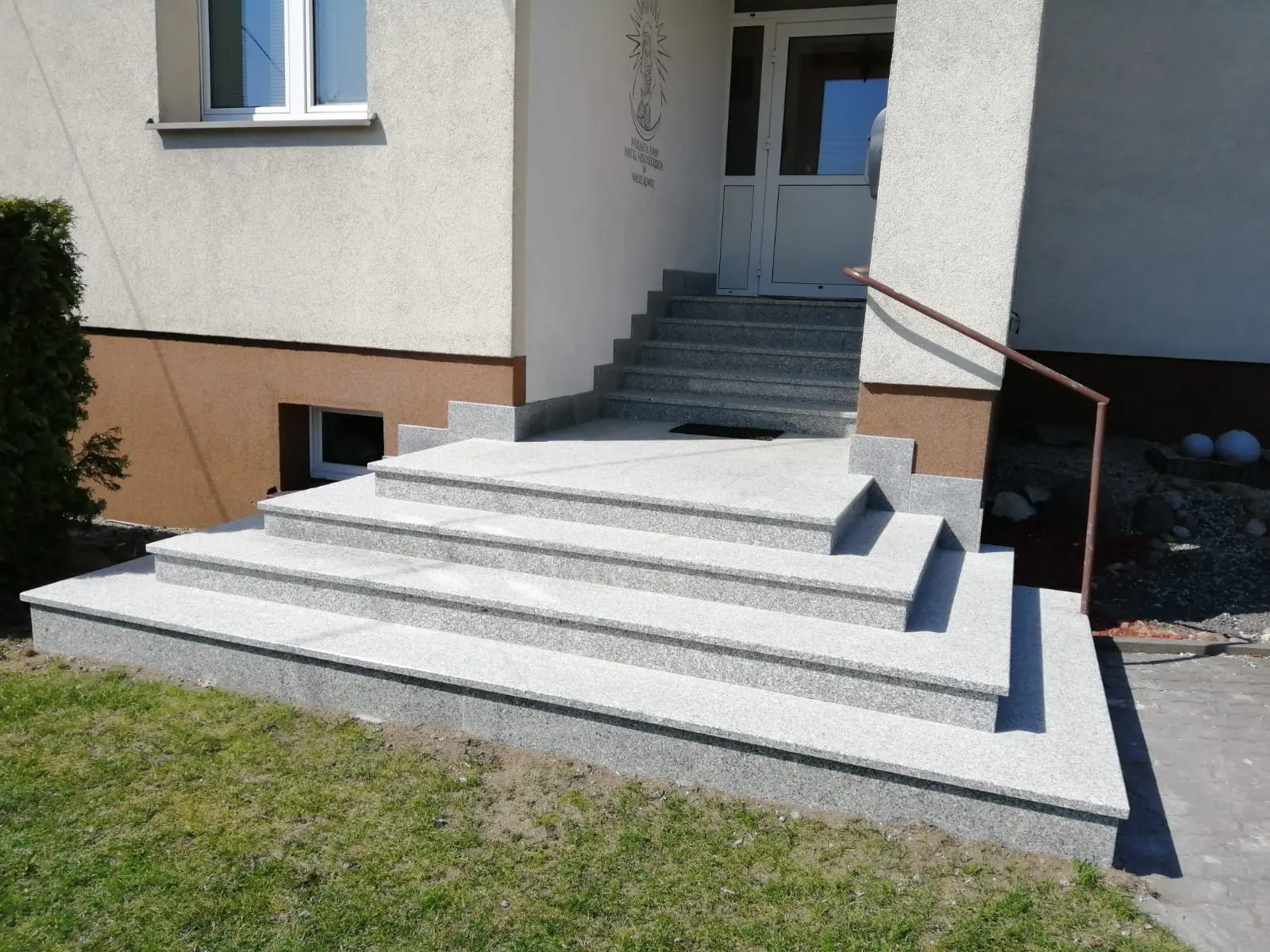 Jasne schody zewnętrzne wykończone ciemnym kamiennym obrzeżem